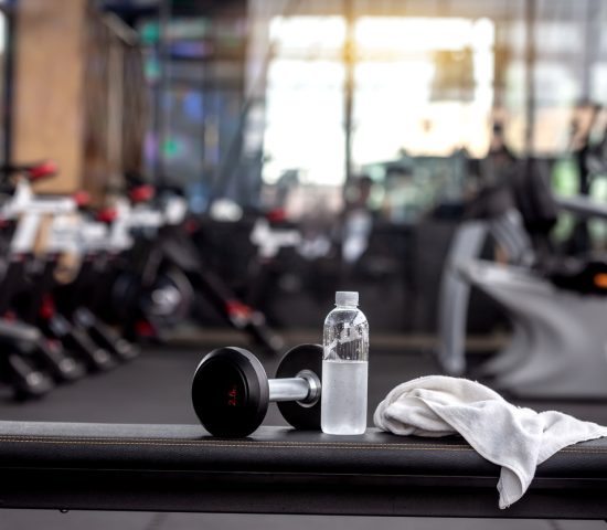 Dumbbell, water bottle, towel on the bench in the gym.